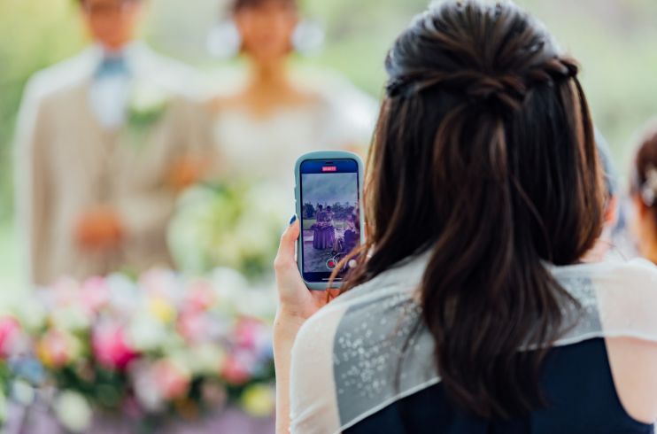 新郎新婦をスマートフォンで撮影する人